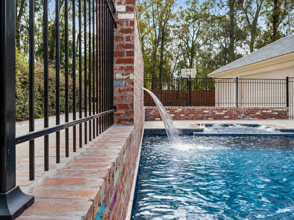 Black aluminum fence panels between brick pillar posts enclosing a backyard in Louisiana