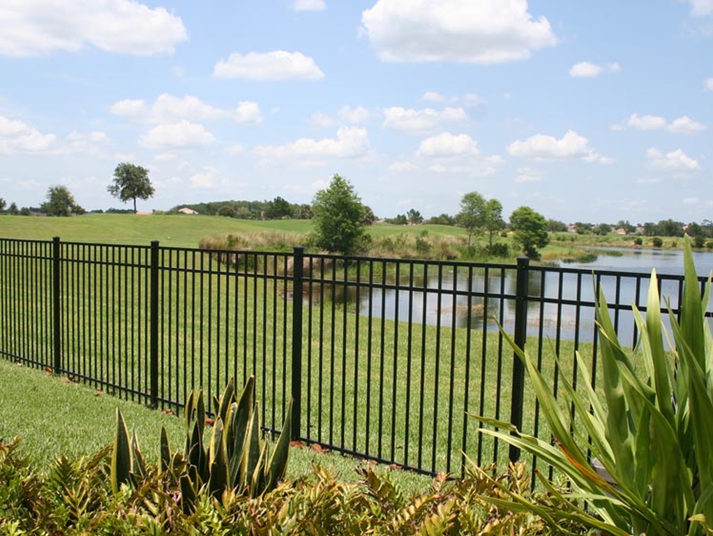 Black aluminum fence with brick column posts enclosing a backyard pool at a new construction home in Baton Rouge