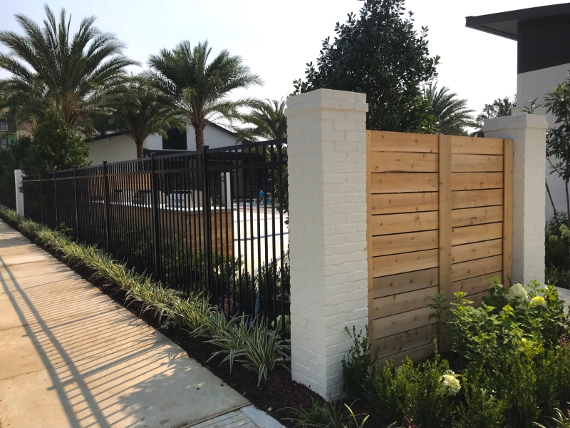 Black aluminum fence paired with a cedar wood privacy fence on a Baton Rouge Commercial property