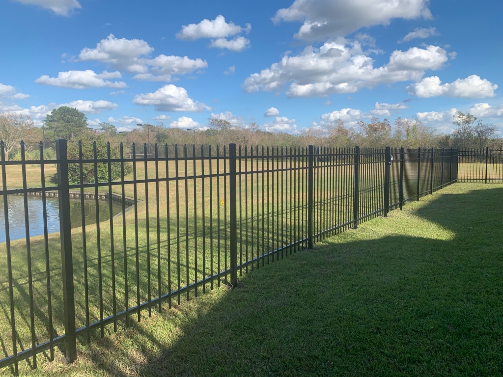 Black ornamental aluminum fence with brick columns running along a waterfront residential property in Baton Rouge, LA